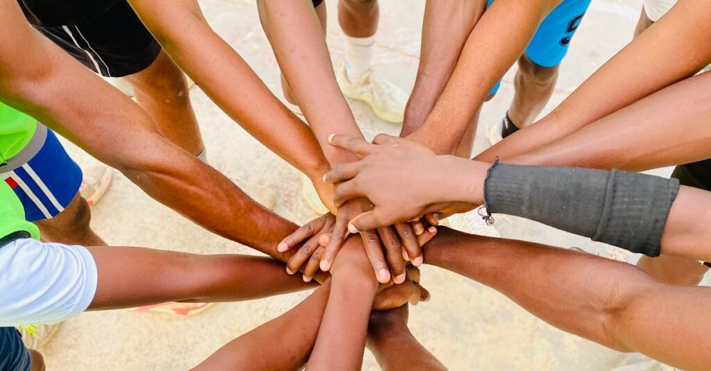 A diverse group of athletes join hands in unity during an outdoor sports session.